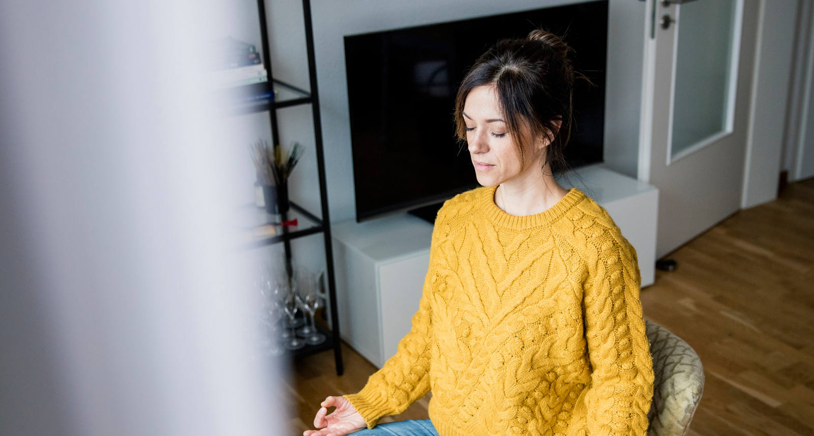 Una donna è seduta in salotto e medita.