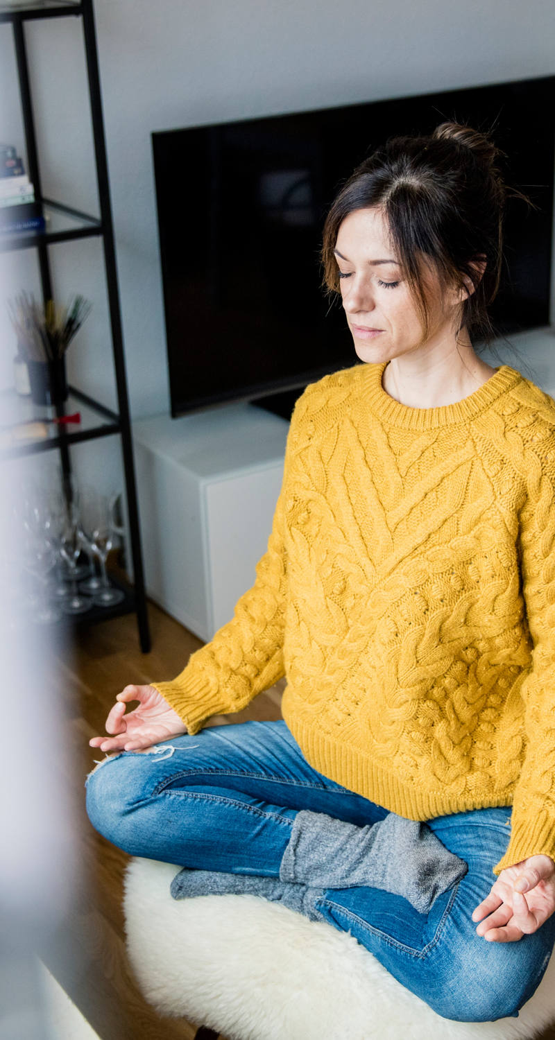 Una donna è seduta in salotto e medita.
