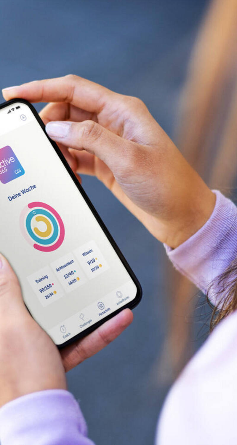 Eine Frau hält ein Handy und betrachtet die active365-App.