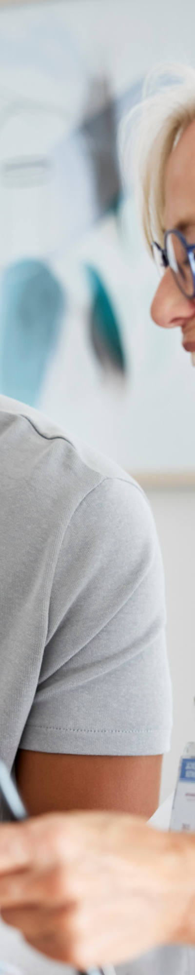 La dottoressa guarda una cartella insieme al suo paziente, sorridendo, e discutono dei risultati mentre sono seduti in una sala di visita.