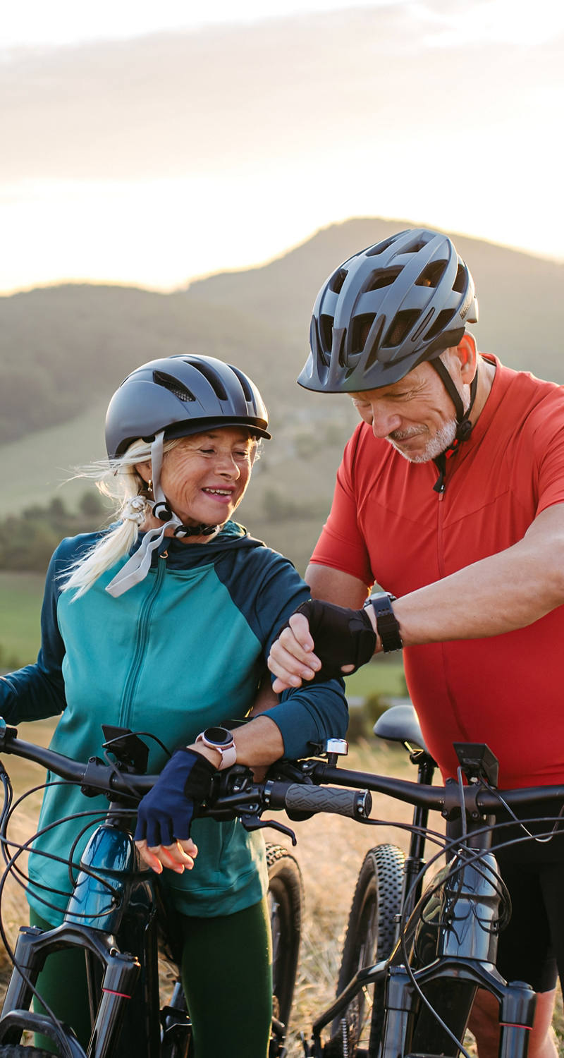 Eine ältere Frau und ein älterer Mann machen eine Velotour in der Natur