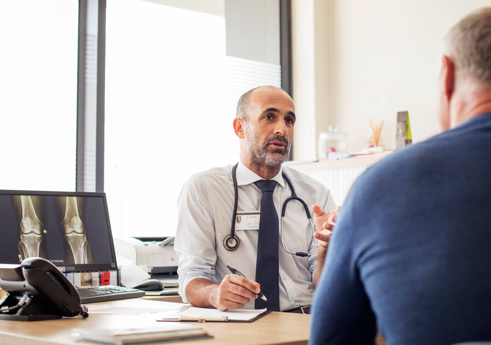 Arzt spricht mit Patient in Arztpraxis.
