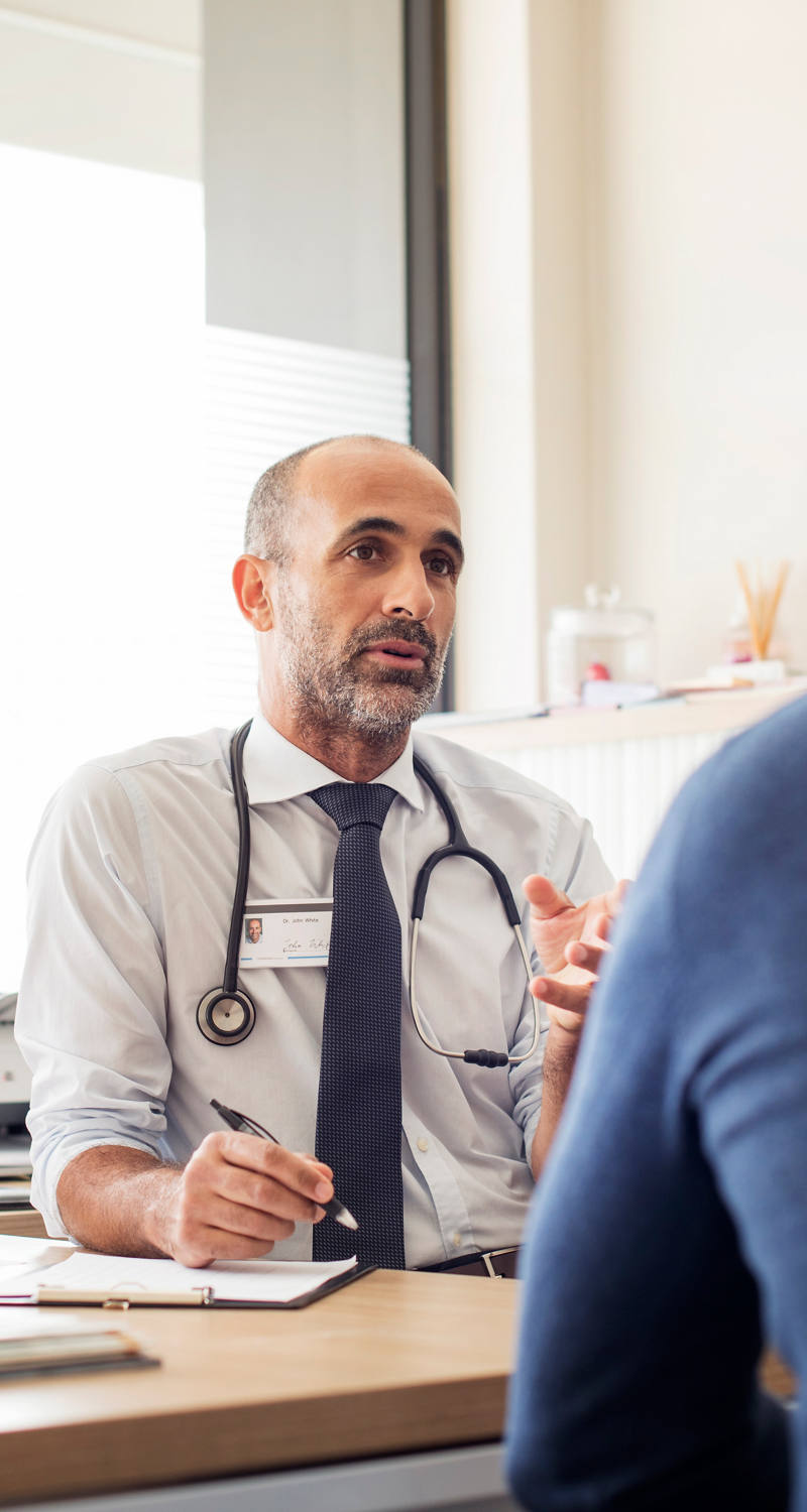 Arzt spricht mit Patient in Arztpraxis.