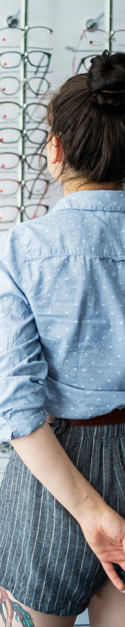 Woman stands in front of frame with glasses.