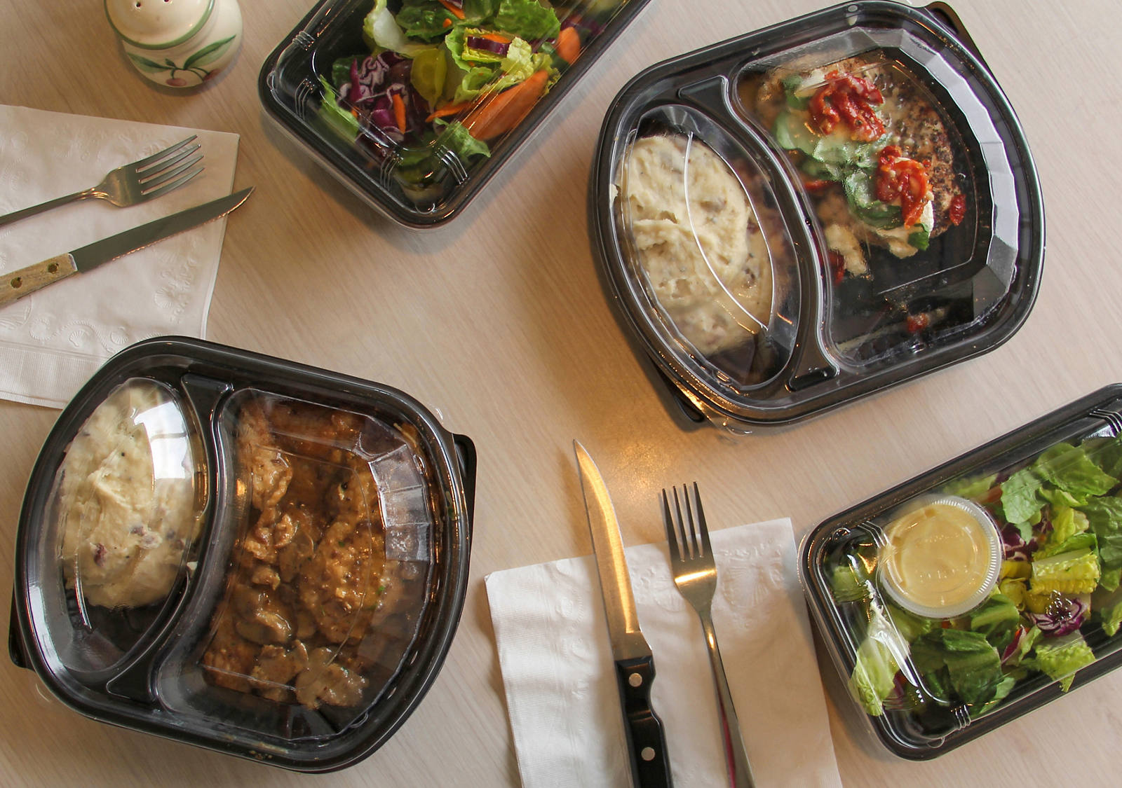 Sur la table se trouvent plusieurs plats industriels pour le repas de midi.