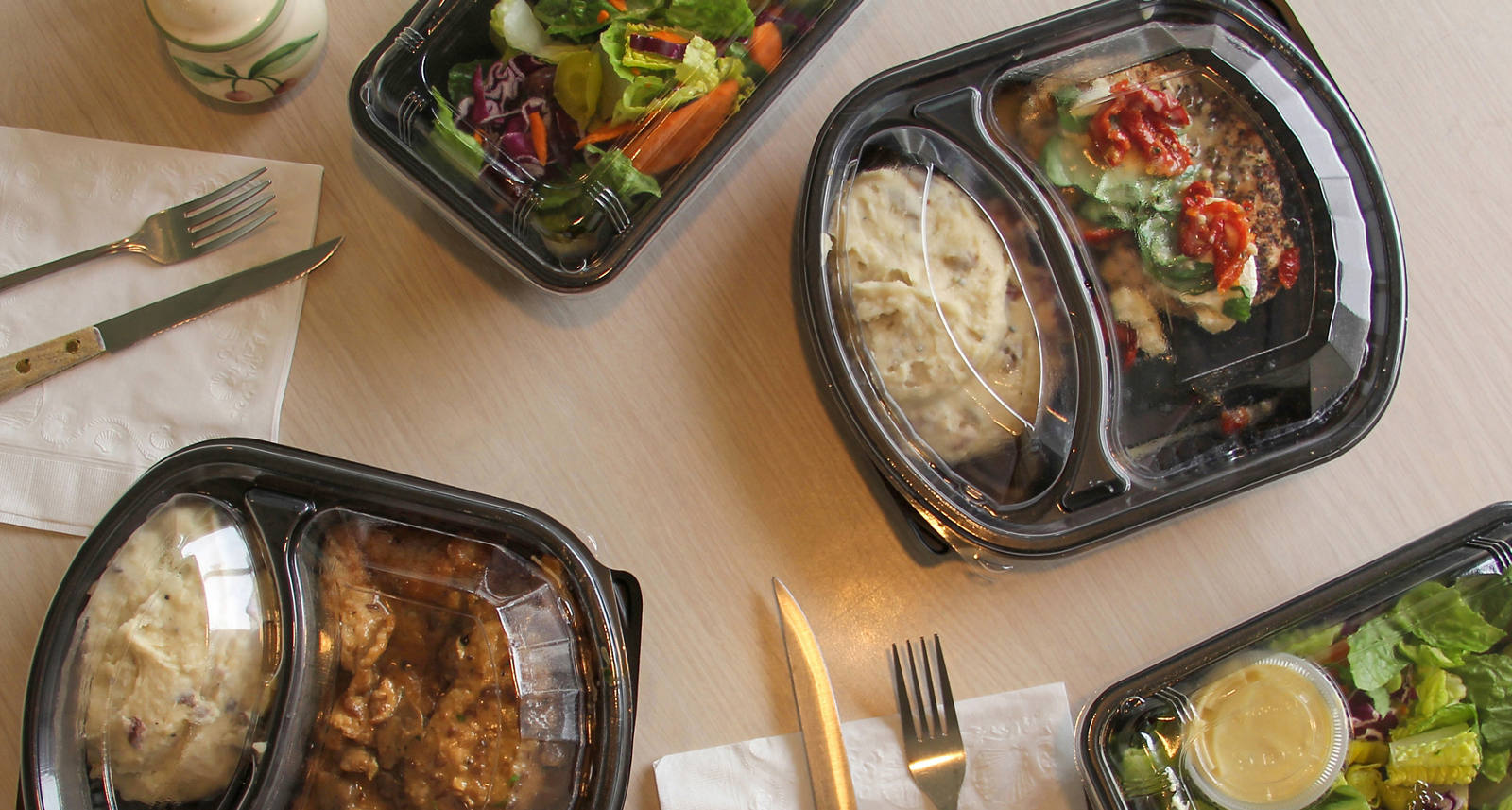Sulla tavola da pranzo diversi menù pronti confezionati.