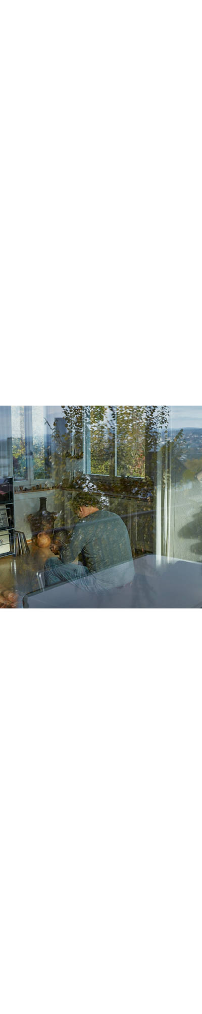 A thoughtful man sits unhappily in his living room.