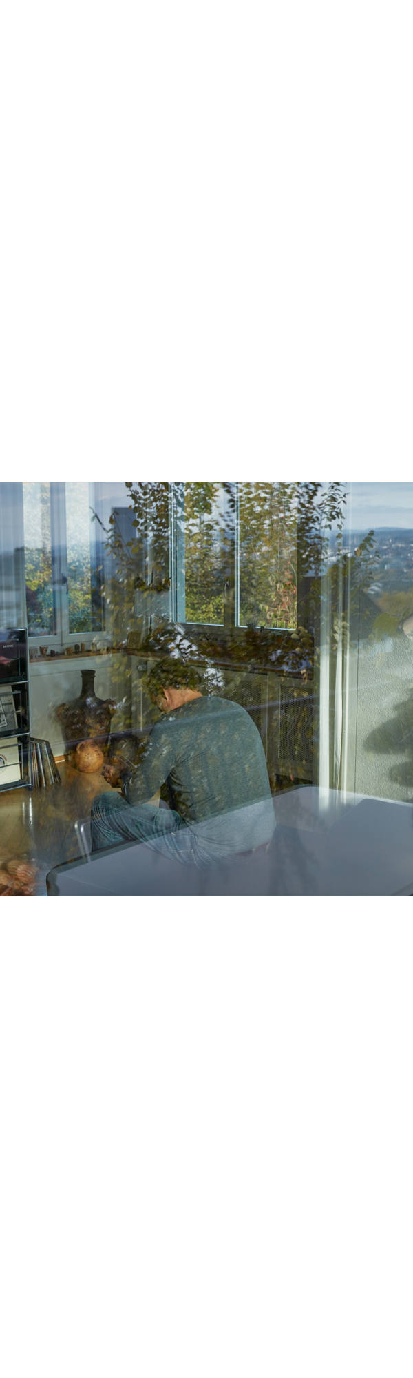 A thoughtful man sits unhappily in his living room.