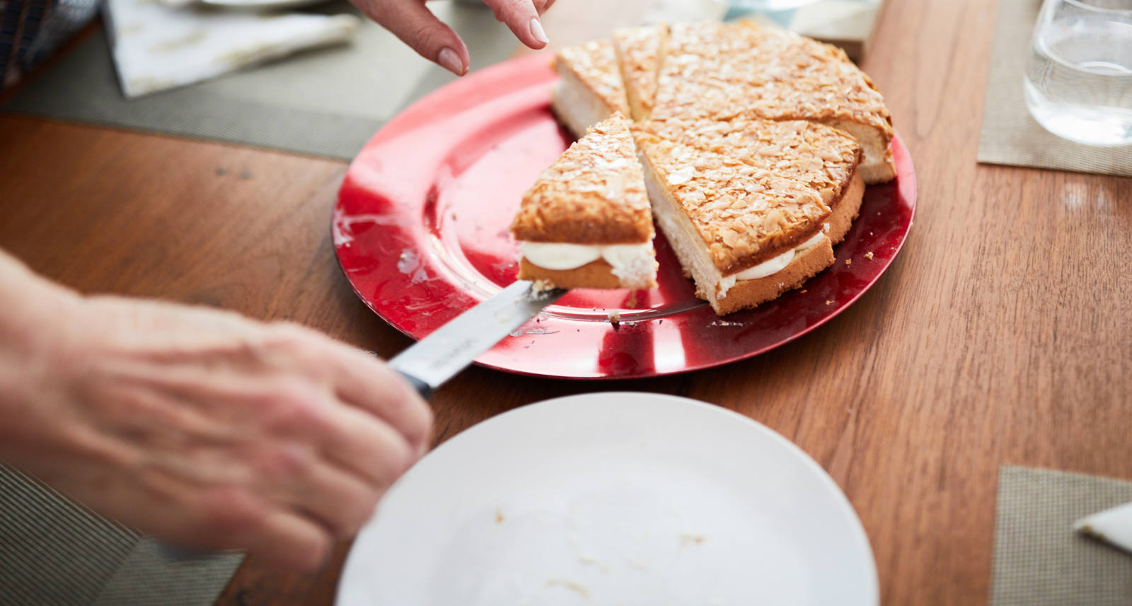 A woman has cut the cake into pieces and arranges the pieces on dessert plates.