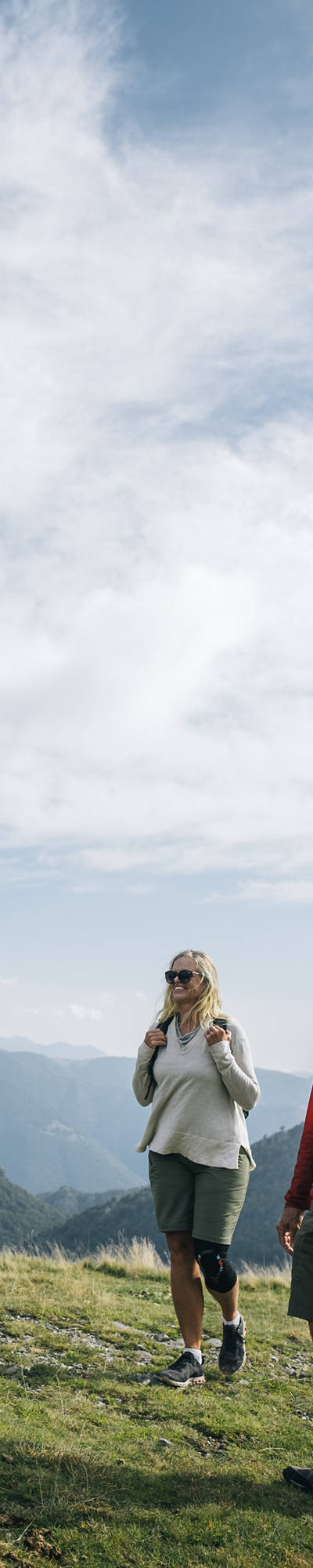 Par beau temps, une famille se promène dans une prairie en montagne et s’amuse.