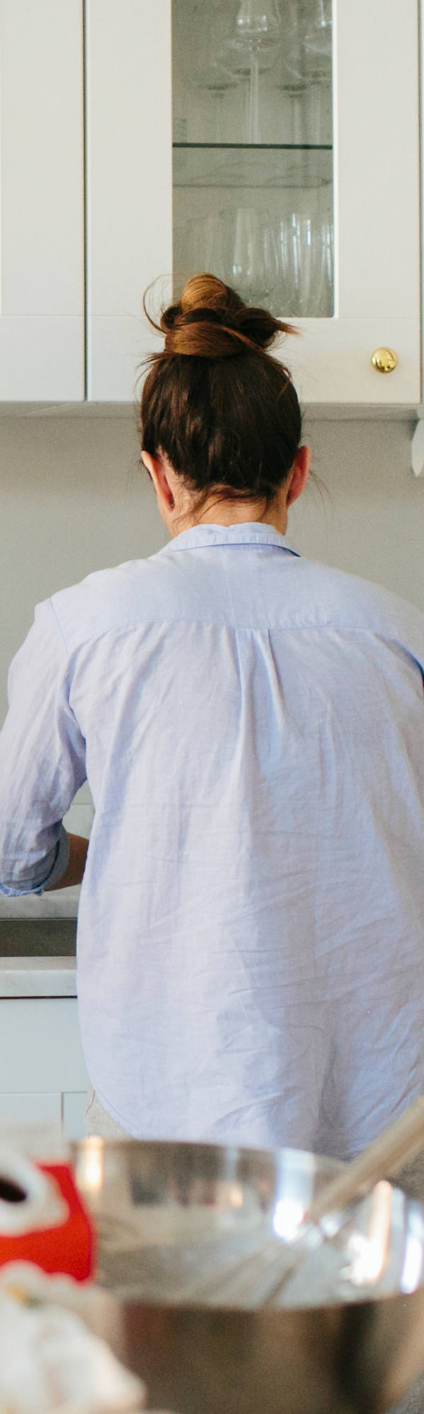 Young family standing together in the kitchen. Father holding a newborn baby and reading the newspaper.
