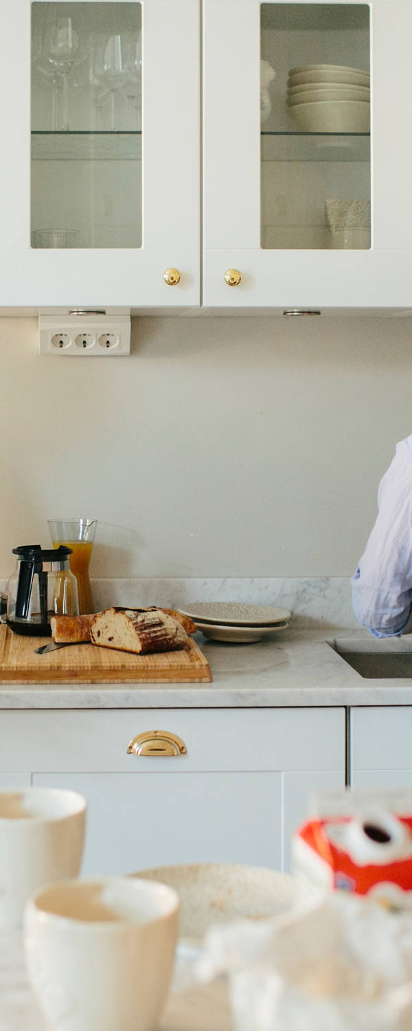 Une jeune famille se tient ensemble dans la cuisine. Le père tient un nouveau-né et lit le journal.