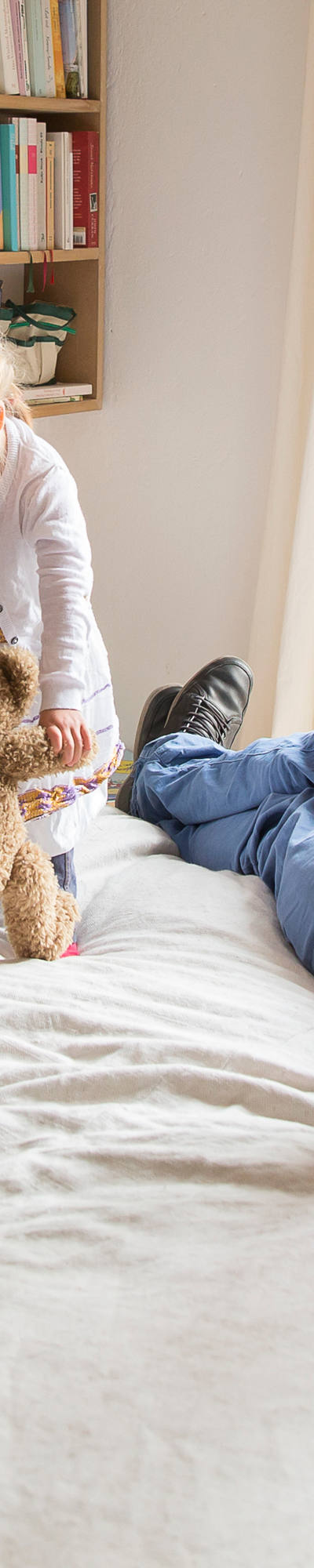 Giovane famiglia infuria sul letto dei genitori. Sullo sfondo è appesa una libreria.