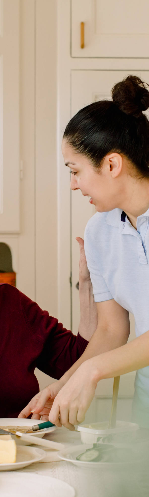 In cucina un’anziana signora riceve sostegno da un infermiere.