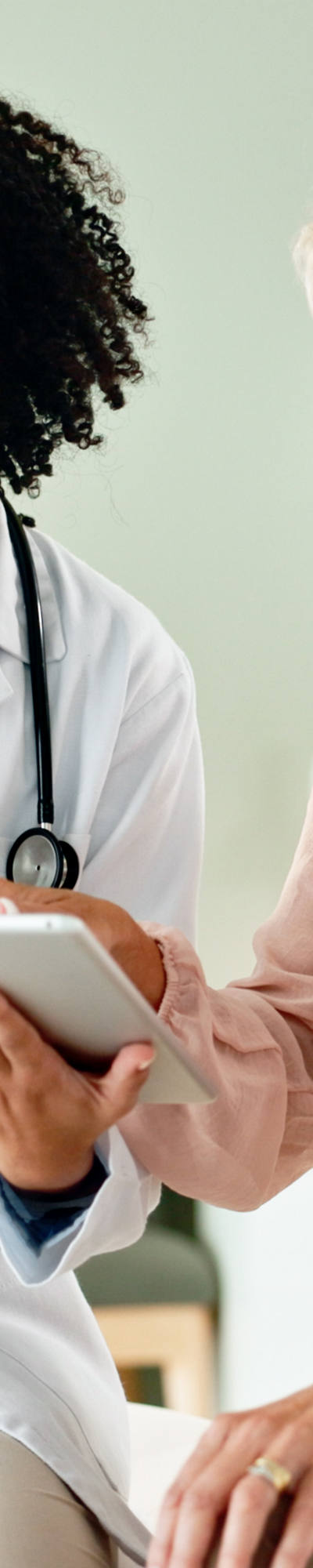 Il medico guarda un dossier digitale con il suo paziente e discute i referti, mentre sono seduti nella stanza delle cure.