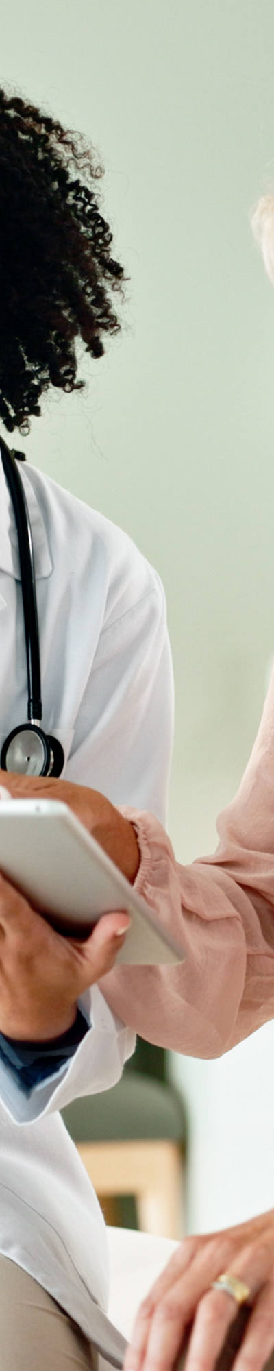 Il medico guarda un dossier digitale con il suo paziente e discute i referti, mentre sono seduti nella stanza delle cure.