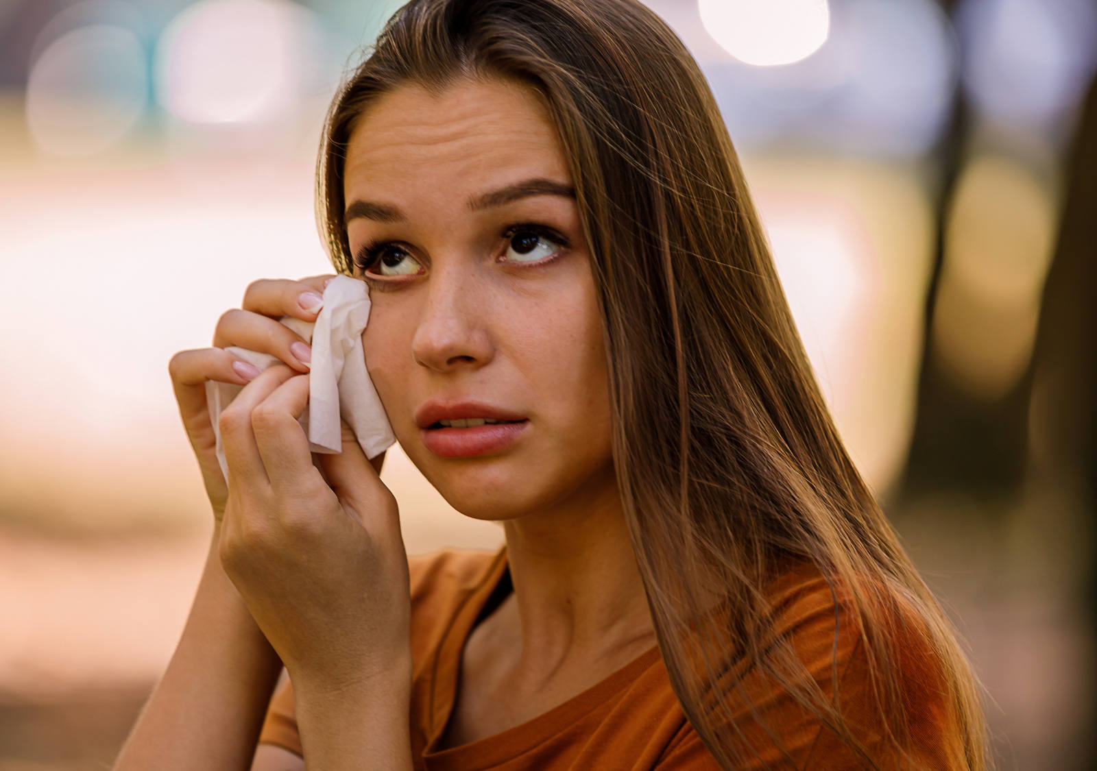 Woman with red eyes wipes her tears with a handkerchief.