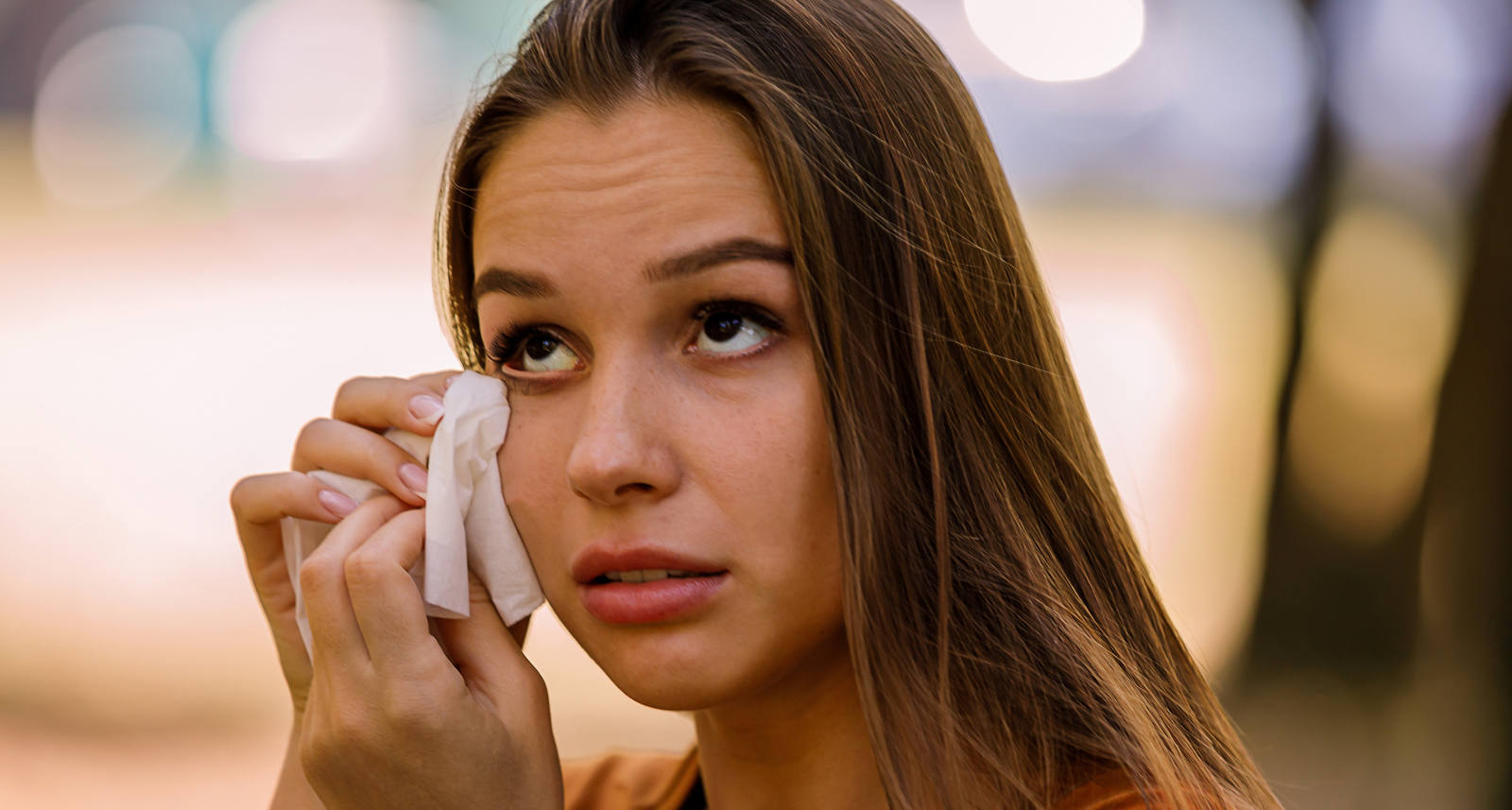 Woman with red eyes wipes her tears with a handkerchief.