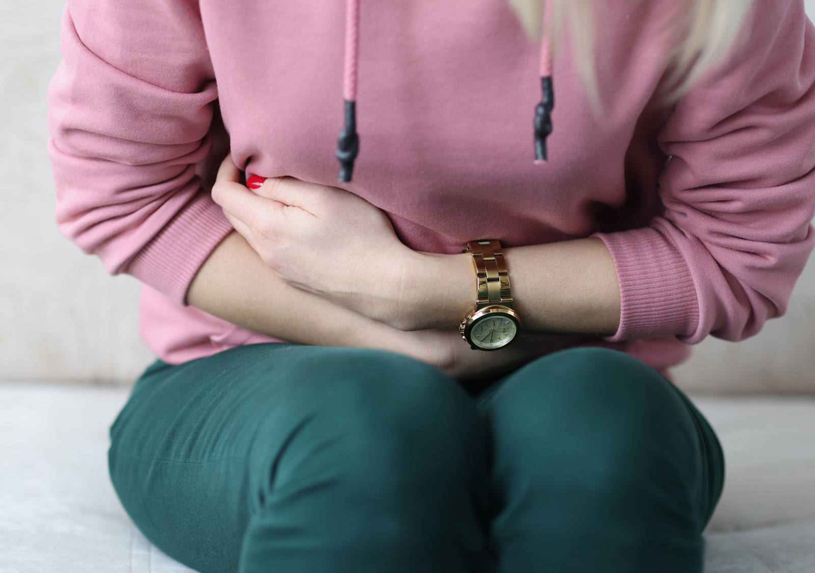 La femme tient ses bras devant le ventre qui a mal.
