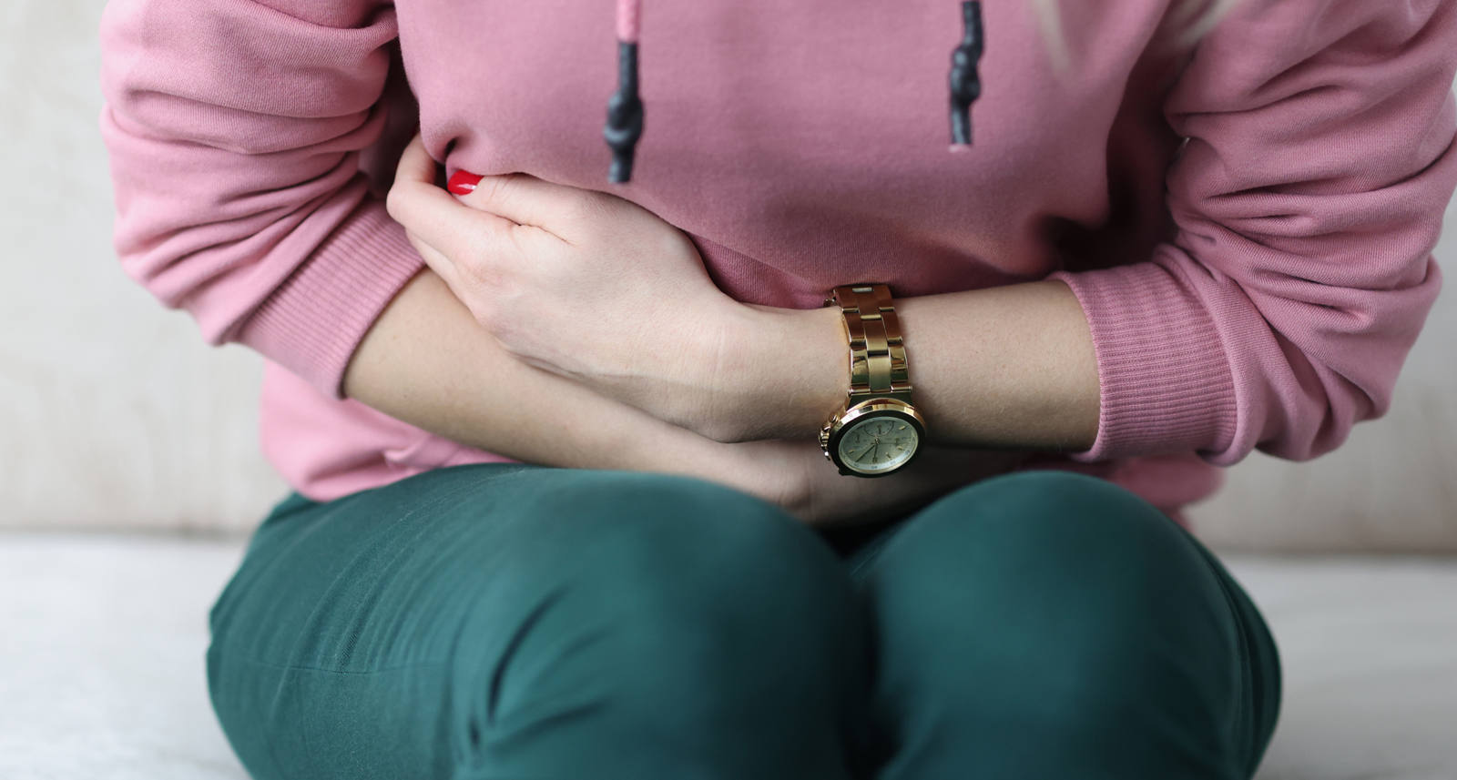 Woman holds her arms in front of aching stomach.