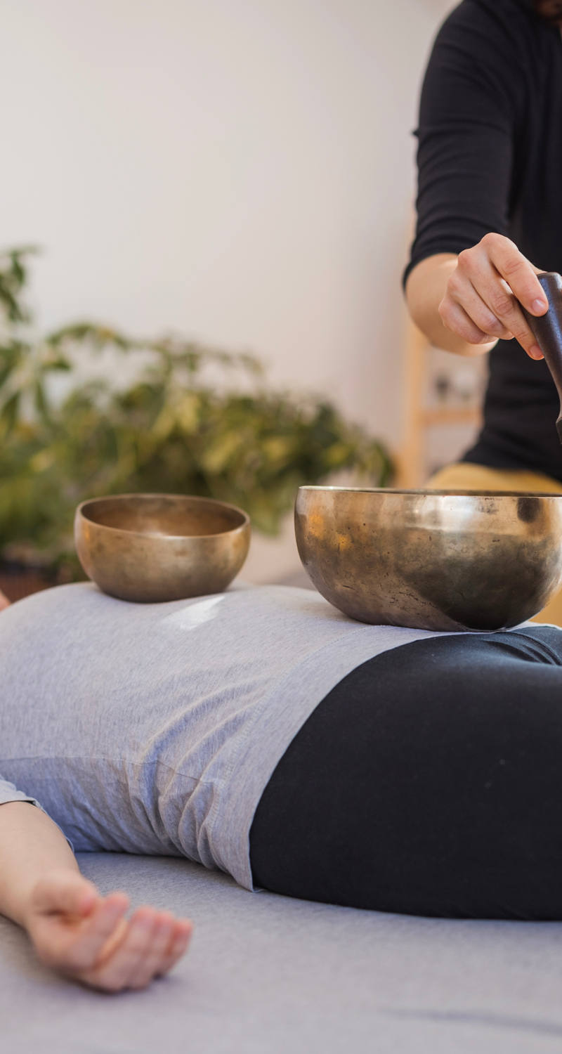  A woman lies relaxed on the floor enjoying singing bowl therapy