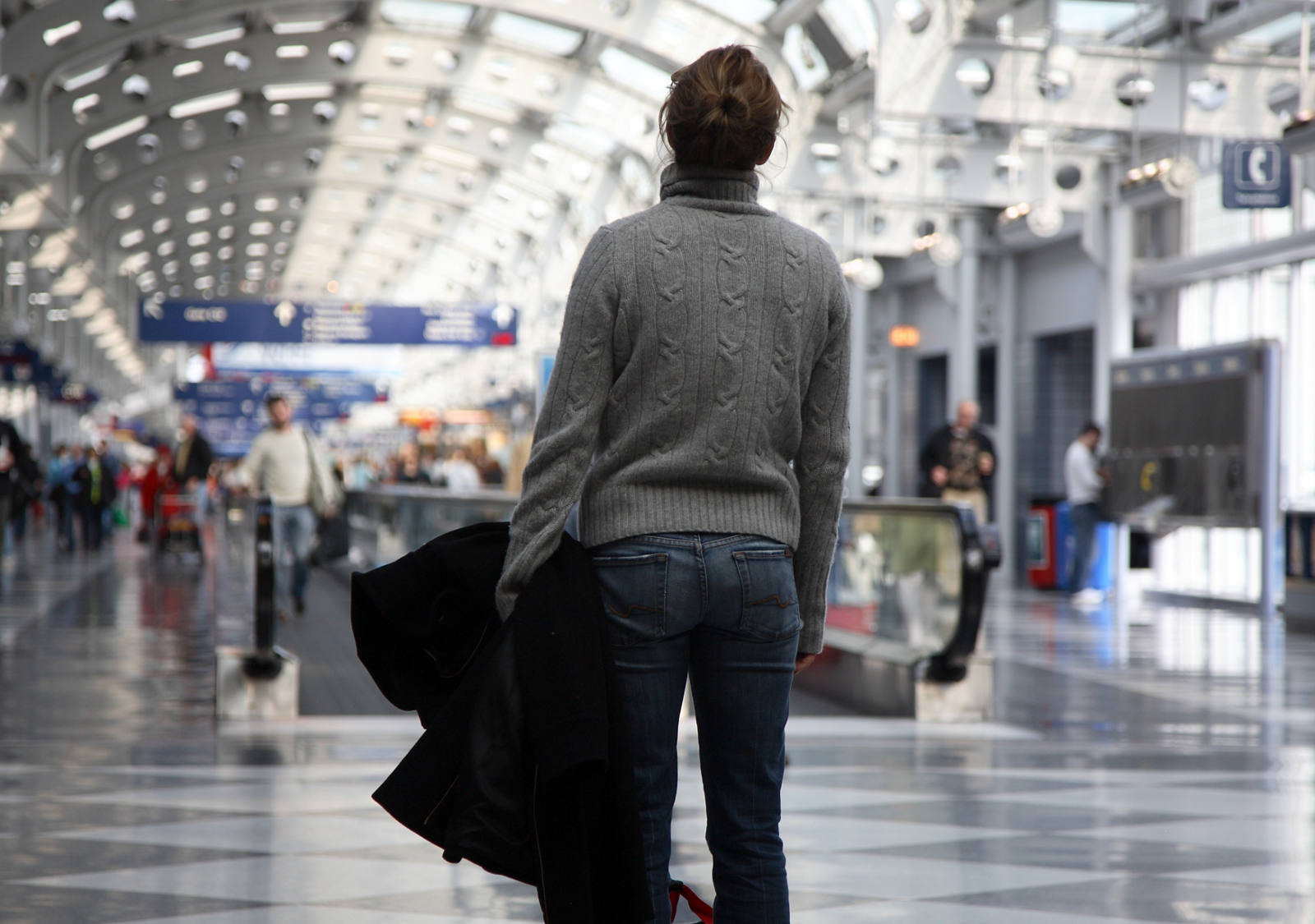 A woman is standing in a crowd at the airport and is stressed by the situation.