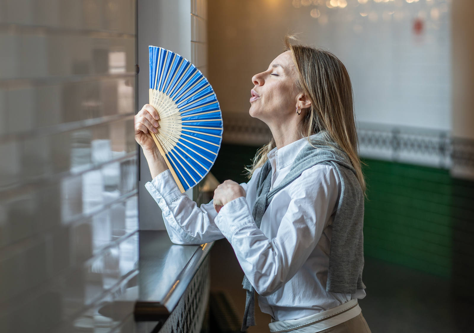 Una calda giornata, la signora è in piedi nel corridoio e cerca con il suo ventaglio di alleviare la sua alta temperatura corporea per evitare di sudare troppo.