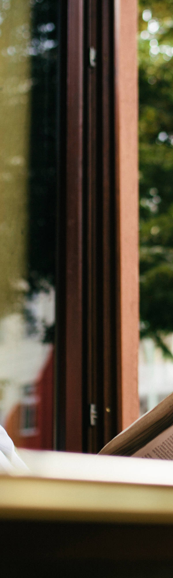 Ältere Frau liest Zeitung bei offenem Fenster