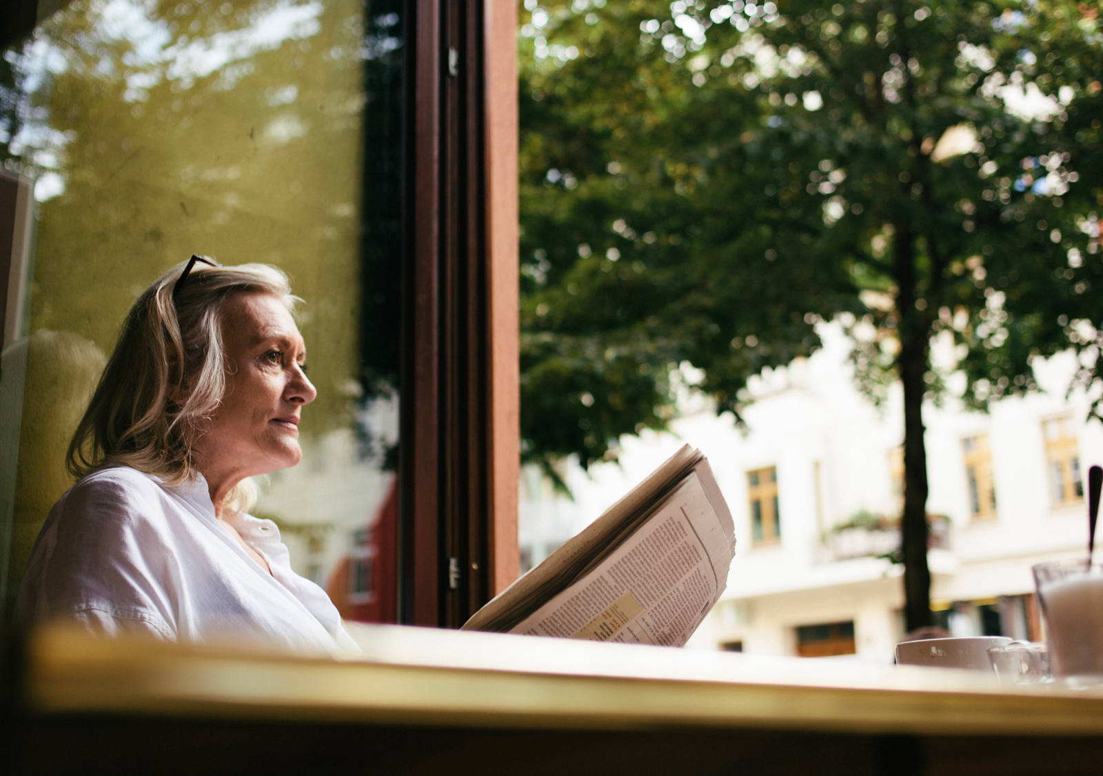 Femme âgée lisant le journal à la fenêtre ouverte