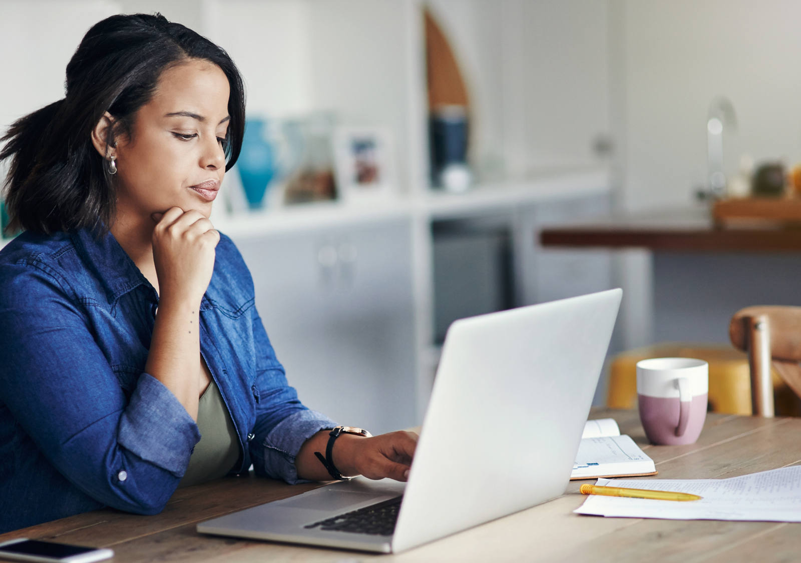 Frau sitzt am Esstisch und arbeitet am Laptop
