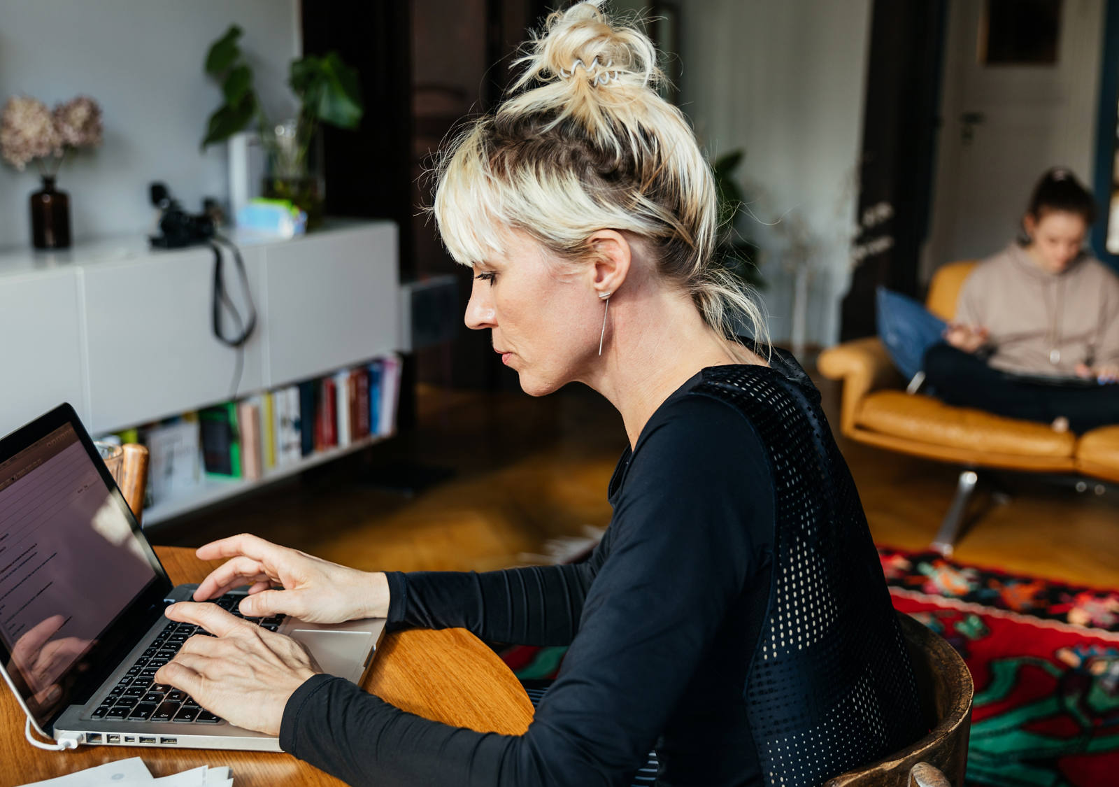 Woman typing on laptop at a table.