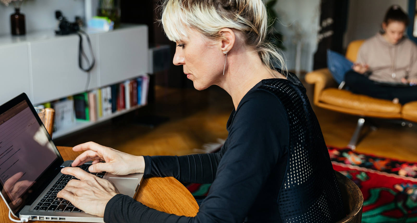 Frau tippt auf Laptop an einem Tisch.