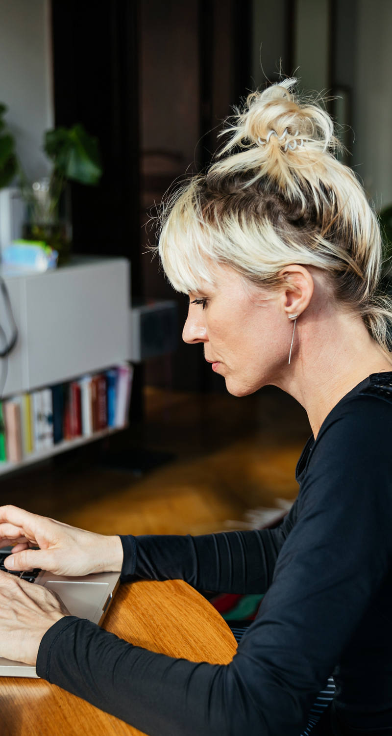 Frau tippt auf Laptop an einem Tisch.