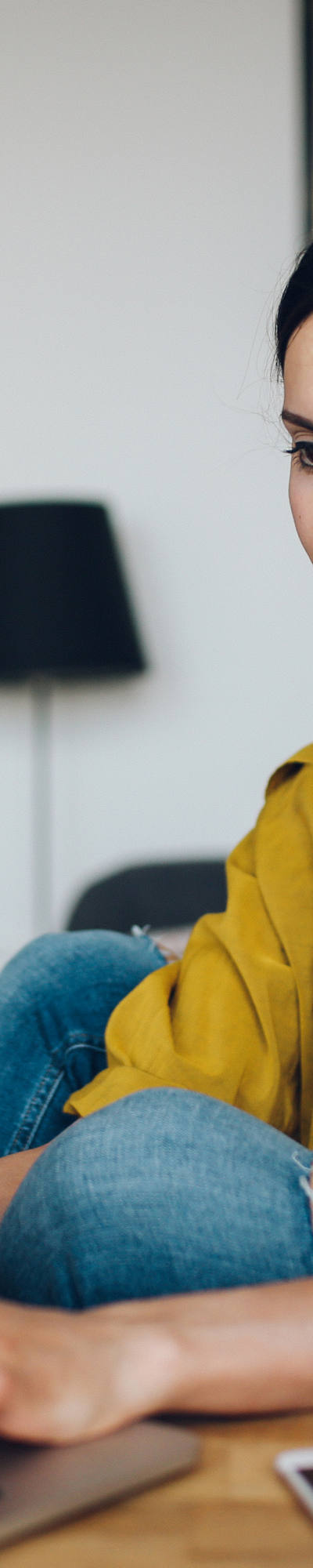 Frau arbeitet am Laptop am Wohnzimmertisch. 