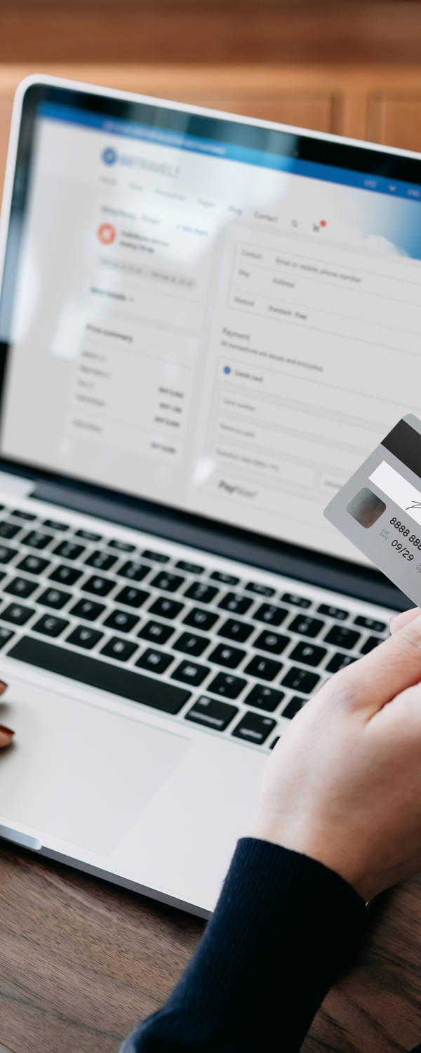 Frau sitzt am Laptop und macht eine Zahlung mit Ihrer Kreditkarte