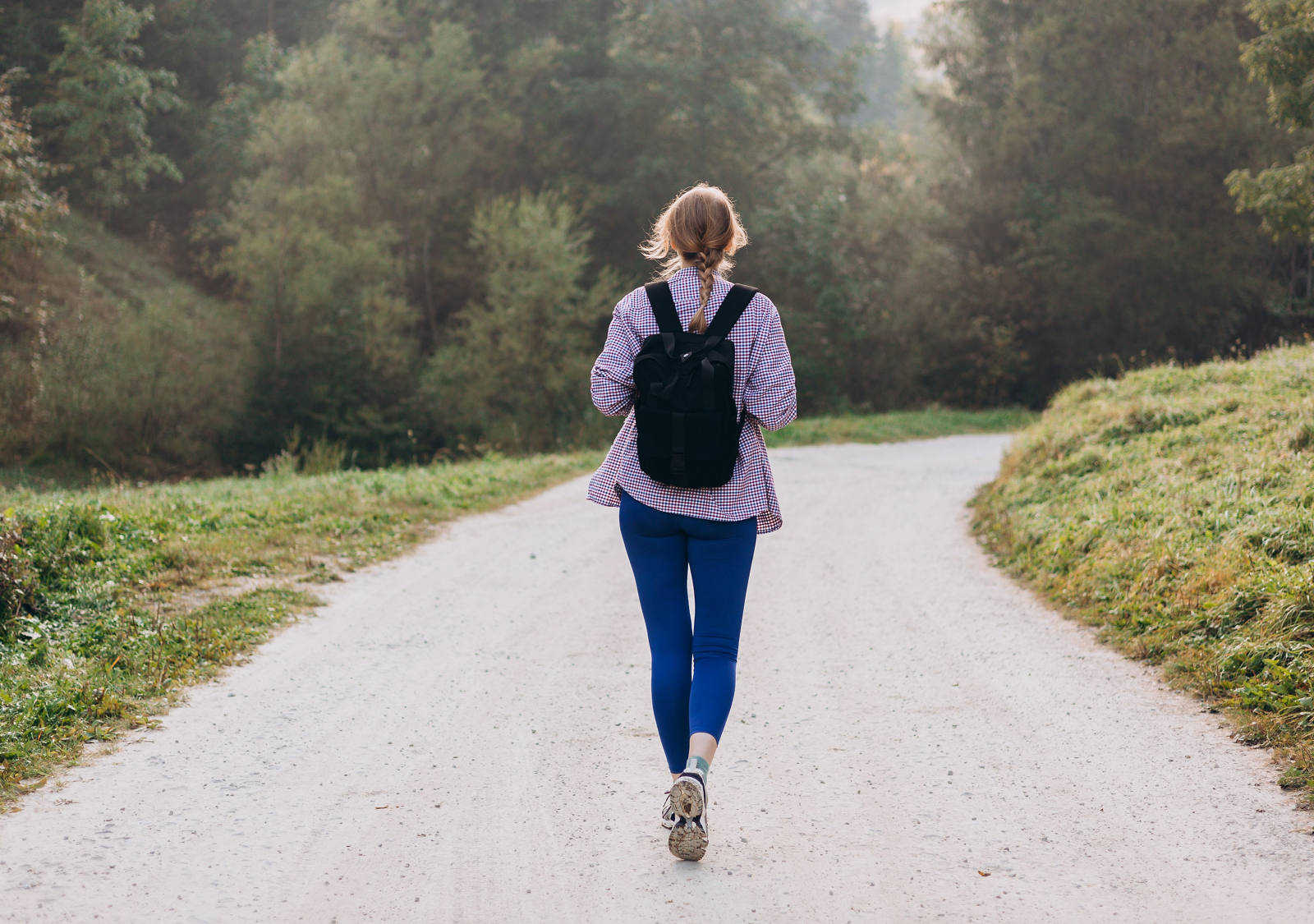 Une femme avec un sac à dos se promène le long d’un sentier en pleine nature.