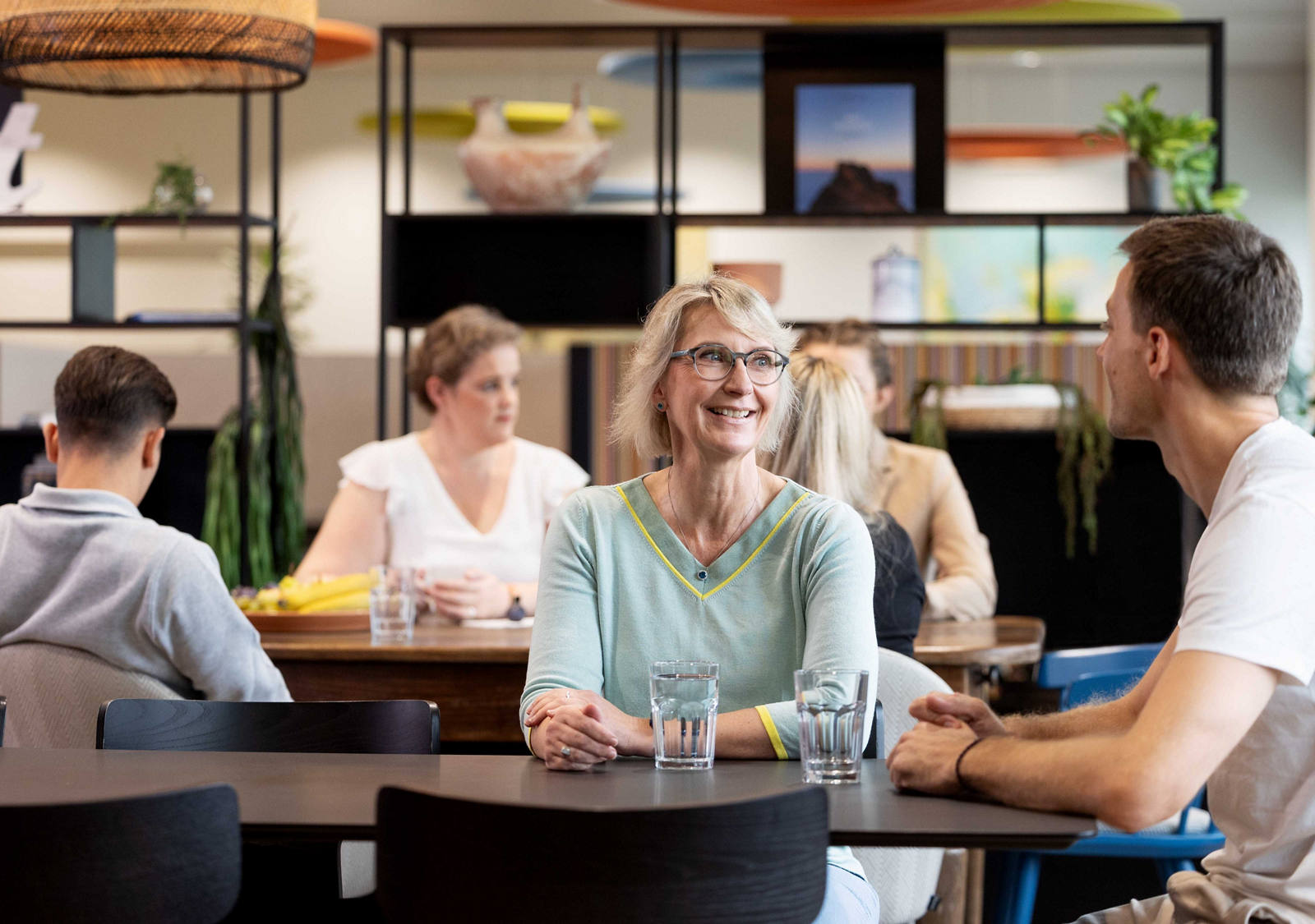 I collaboratori e le collaboratrici della CSS sono seduti nella caffetteria della CSS e chiacchierano.