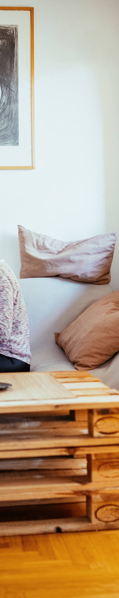 Une femme avec presque pas de cheveux et son partenaire sont assis sur le canapé dans le salon et jouent heureux avec le chat.