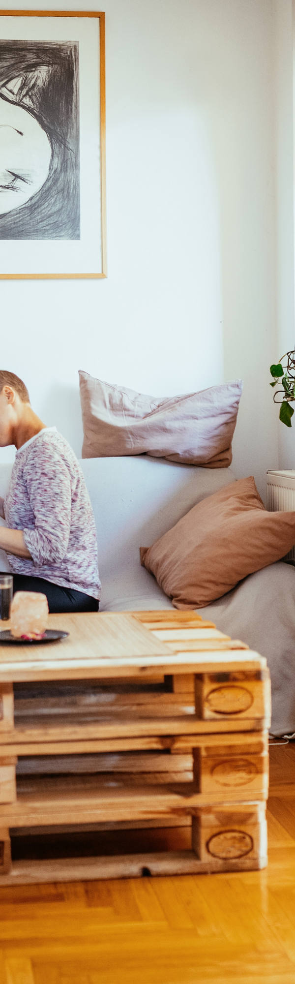 Une femme avec presque pas de cheveux et son partenaire sont assis sur le canapé dans le salon et jouent heureux avec le chat.
