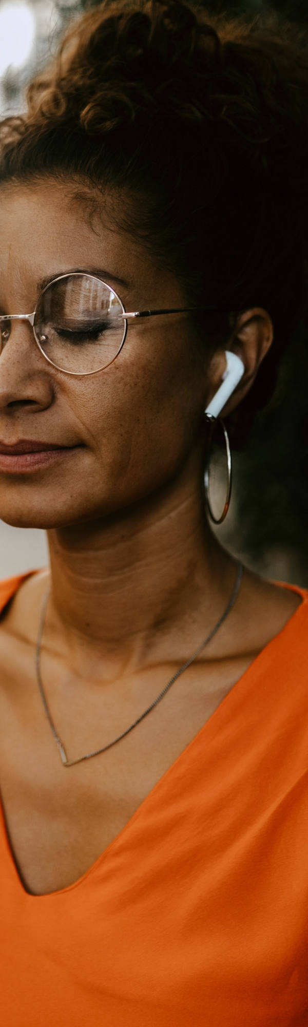 Frau meditiert mit geschlossenen Augen und Kopfhörern in den Ohren