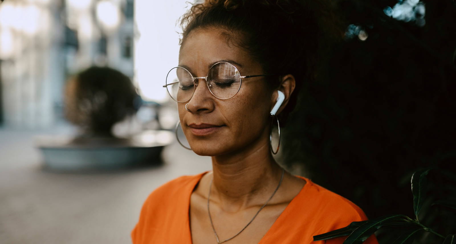 Donna medita con gli occhi chiusi e le cuffie nelle orecchie