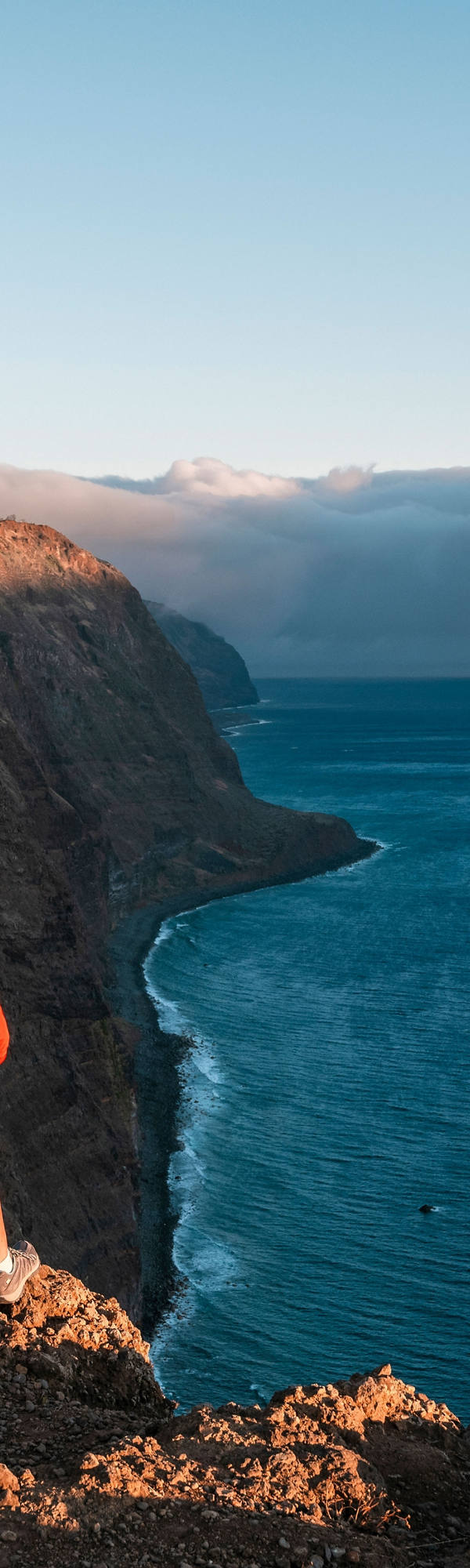 Jeune femme avec le sac à dos regardant en bas des falaises sur la baie de mer