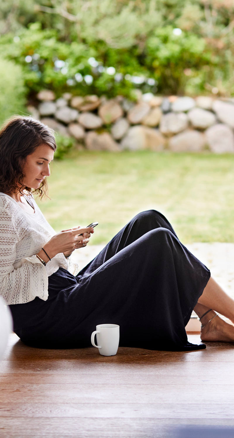 Frau sitzt in Gartentür am Smartphone