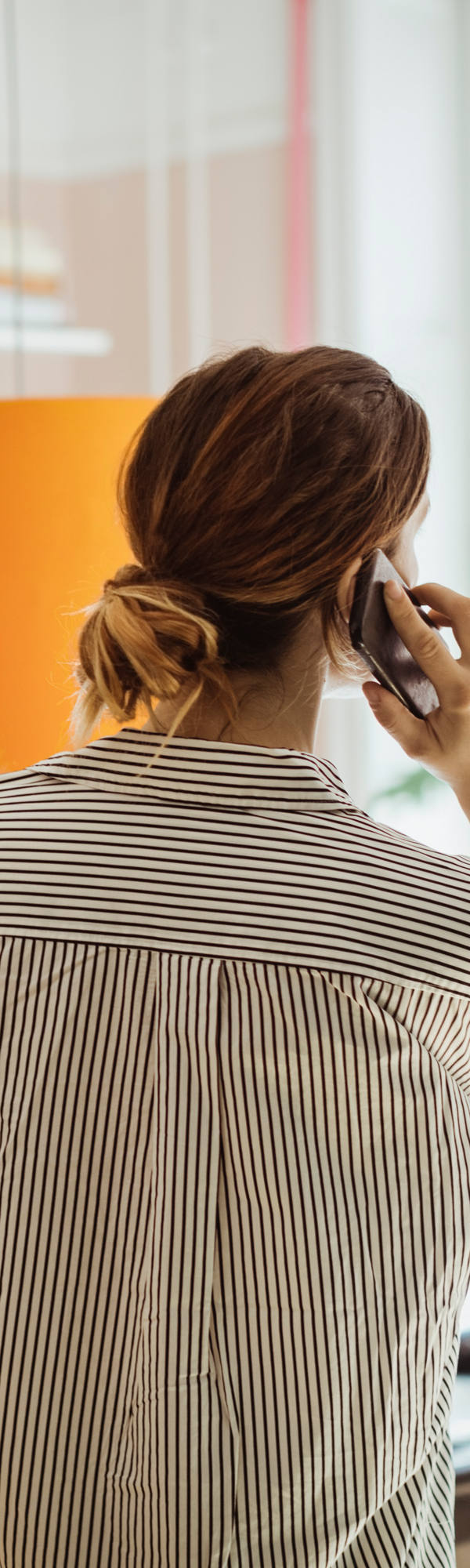 Mother with toddler on her arm stands in her office talking on the phone.