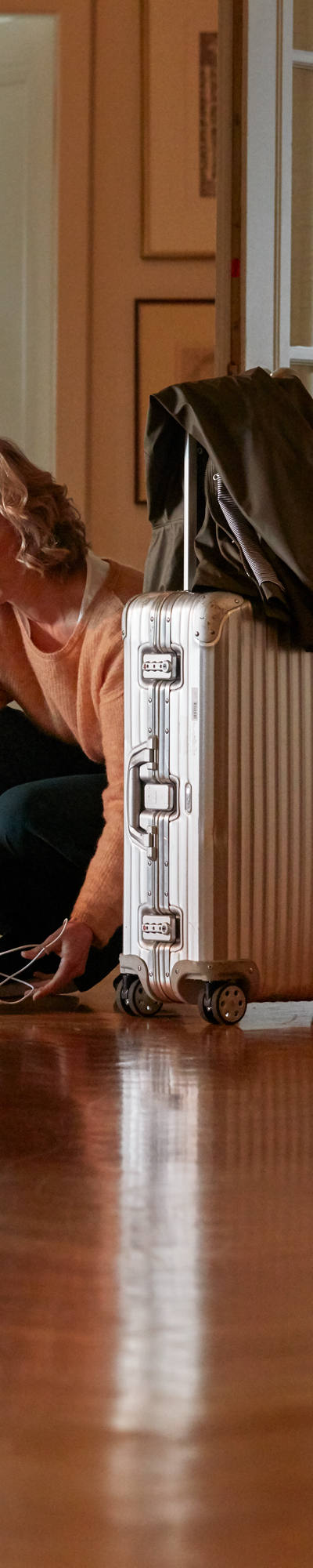 Woman packing suitcase in hallway of her apartment