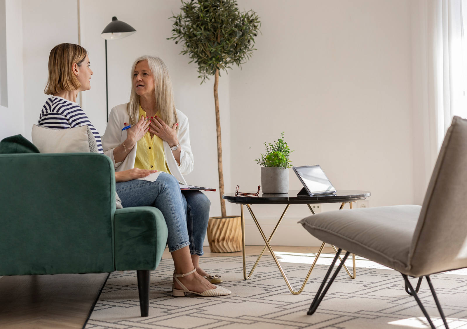 Durante il coaching, una donna si siede sul divano in un’accogliente sala riunioni e parla con la sua terapista.