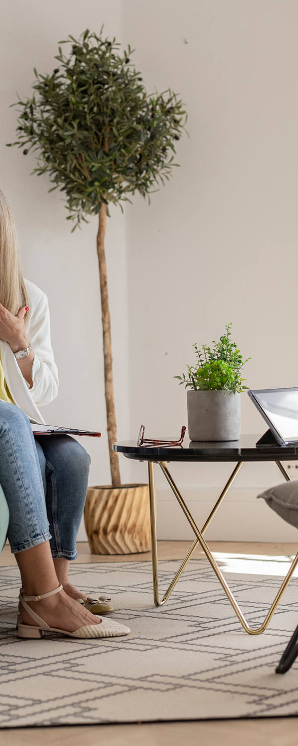 Eine Frau sitz während dem Coaching in einem gemütlichen Besprechungs-Zimmer auf dem Sofa und spricht mit ihrer Therapeutin.