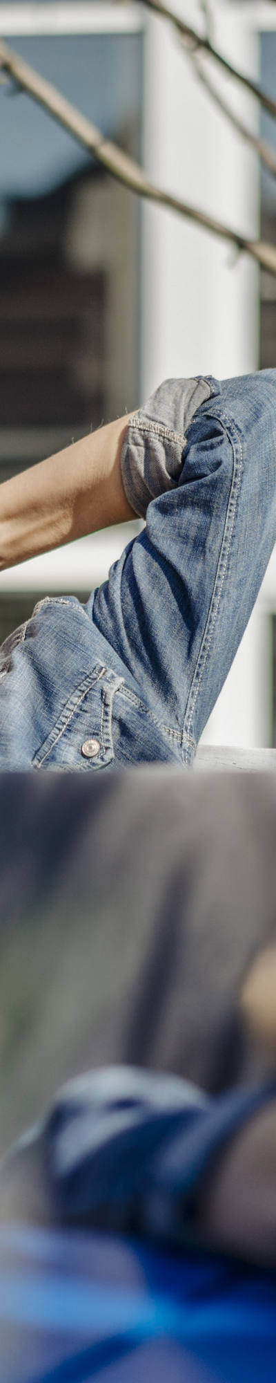 Una donna anziana è distesa rilassata su una panchina in giardino e si gode i raggi del sole ad occhi chiusi.