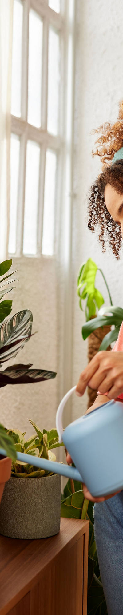  In her home, a woman watering the plants relaxed.