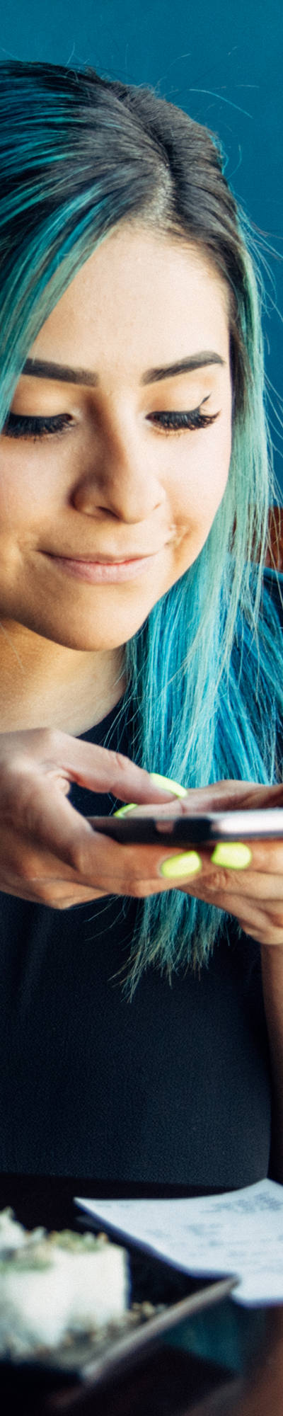 Junge Frau mit blauen Haaren fotografiert mit Smartphone eine Rechnung